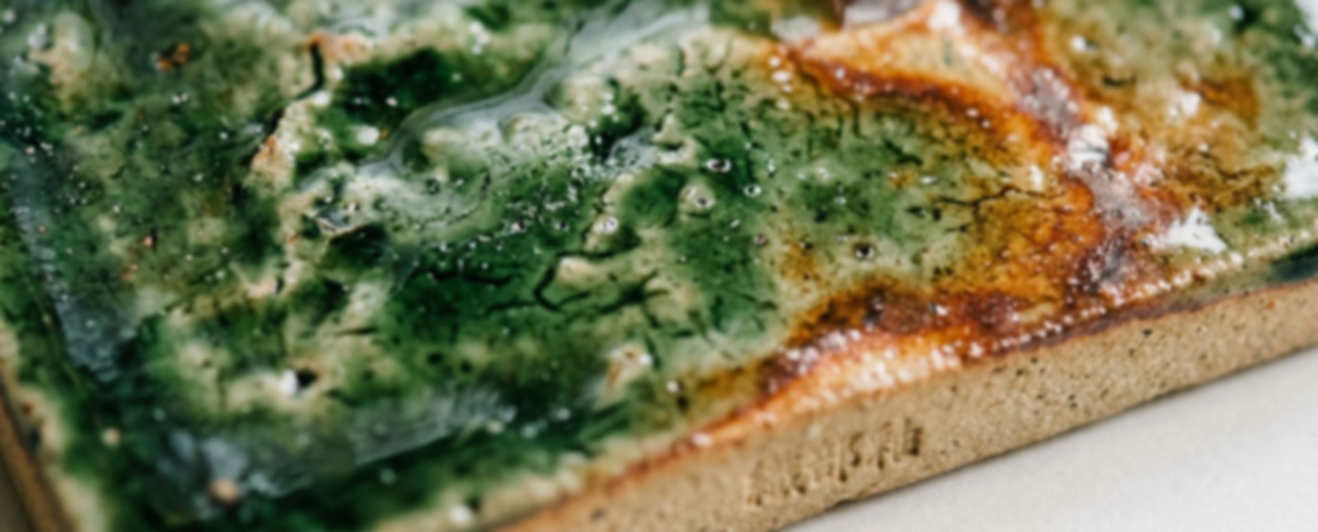 Oribe glaze macro — deep green and amber on raw clay